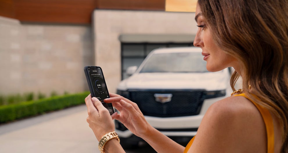 lady checking her mobile with a Cadillac vehicle background | Earnhardt Cadillac in Scottsdale AZ