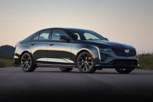 A black 2022 Cadillac CT4 angled right in front of greenery.
