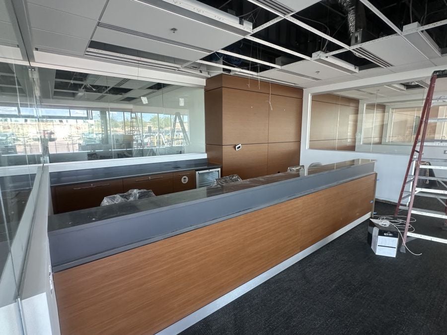 New wood-panel reception desk at Earnhardt Cadillac with open ceiling grid during renovation
